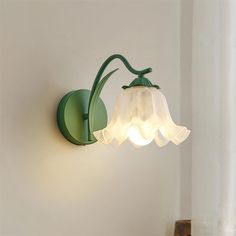 a green wall light with a white flower on it