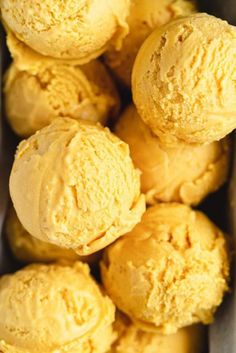 several scoops of yellow ice cream in a metal container on top of a table