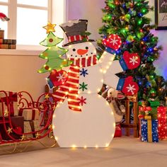 a snowman is standing next to a christmas tree