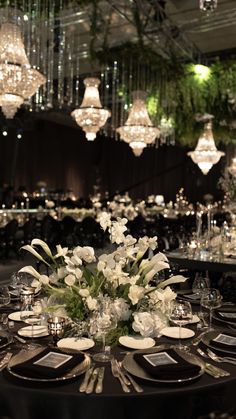 the table is set for an event with chandeliers hanging from the ceiling and flowers in vases