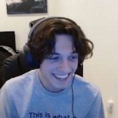 a young man wearing headphones smiles at the camera