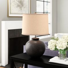 a table with a lamp on top of it next to a vase filled with flowers