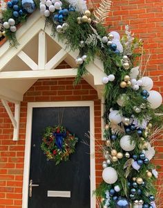 a christmas wreath on the front door of a brick house decorated with ornaments and greenery