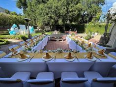 a long table set up with plates and place settings for an outdoor dinner or party