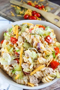 a white bowl filled with pasta salad on top of a wooden table