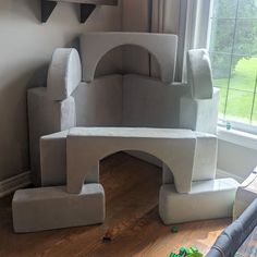 a castle made out of cardboard sitting on top of a hard wood floor next to a window