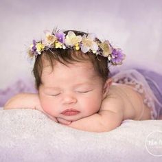 a newborn baby wearing a flower crown on her head