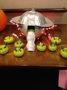 a table topped with lots of green apples under a metal dome covered in lights and decorations