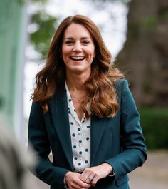 a smiling woman in a green blazer and white shirt