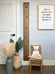 a teddy bear sitting on a chair next to a tall wooden ruler and potted plant