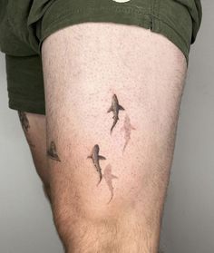 a man with tattoos on his legs and some birds in the air above him,