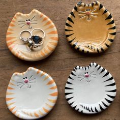 three plates with cats painted on them sitting on a wooden table next to each other