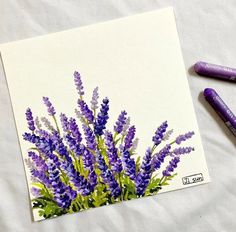 some purple flowers and two markers on a sheet of paper with watercolor pencils