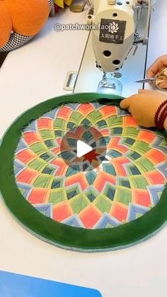 a person is using a sewing machine to sew on a piece of paper with colorful designs