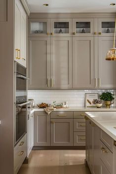 a kitchen with gray cabinets and white counter tops, gold accents on the doors and drawers