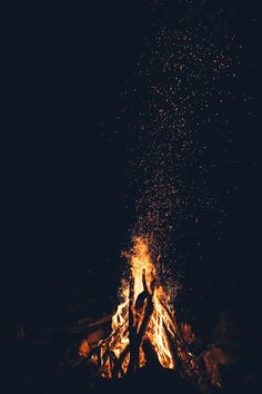 two people standing in front of a campfire with their hands up and arms raised