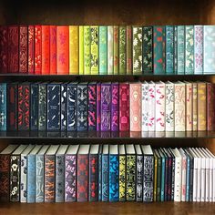 the books are lined up on the shelves in front of each other, all brightly colored