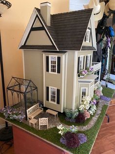 a doll house is on display in a room with flowers and other things around it