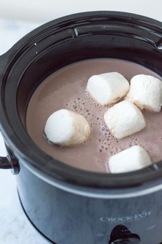 marshmallows are placed in the hot chocolate in an electric crock pot