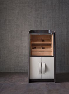 an old fashioned refrigerator with its door open in a room that has grey walls and flooring