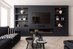 a living room with black furniture and a flat screen tv mounted on the wall above it