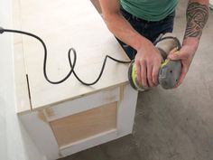 a man is sanding the top of a cabinet with a grinder and power tool