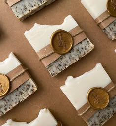 several soap bars with wax and gold buttons on top of each one, sitting on a brown surface