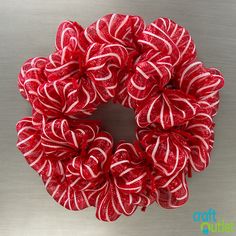 a red and white candy cane wreath sitting on top of a metal surface