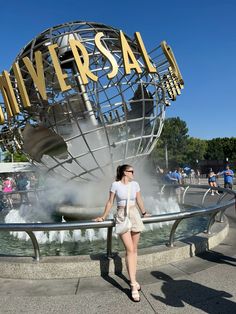 a woman standing in front of a fountain with the word universal on it's side