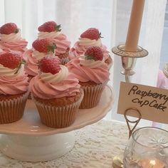 cupcakes with pink frosting and strawberries on top sit on a plate