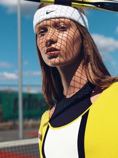 a woman with a tennis racket on her head wearing a yellow and black top