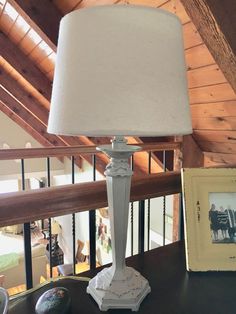 a lamp sitting on top of a wooden table next to a framed photo and an empty picture frame