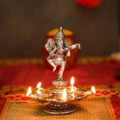 a silver statue sitting on top of a metal tray filled with lit candles and other items