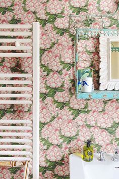 a bathroom with floral wallpaper and a white sink in front of a towel rack