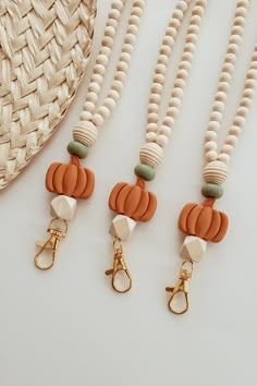 three necklaces and a hat on a white table next to a straw bag with beads