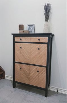 a black and wood dresser next to a white wall