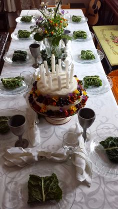 a table topped with a cake covered in white frosting and lots of green leaves