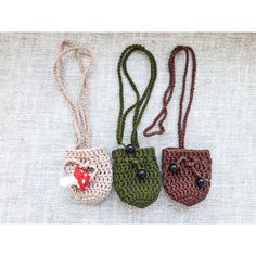 three small crocheted purses are sitting on a white tablecloth, one is green and the other is brown