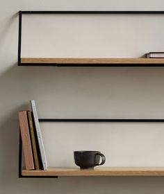 two shelves with books and a cup on them