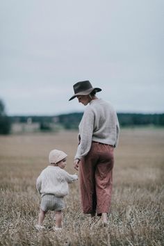 a woman holding the hand of a small child in a field