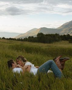 a man and woman laying in tall grass