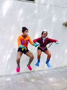 two people dressed in costumes jumping up into the air