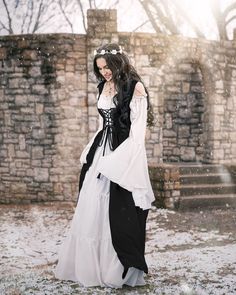 a woman in white and black dress standing on snow covered ground