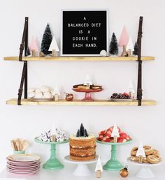 an assortment of desserts and pastries displayed on wooden shelves in front of a white wall