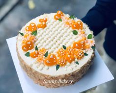 a decorated cake sitting on top of a piece of paper with orange and white frosting