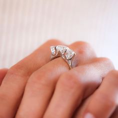 a woman's hand holding an engagement ring with two pear shaped diamonds on it