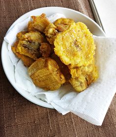 a white plate topped with fried food on top of a table next to a window