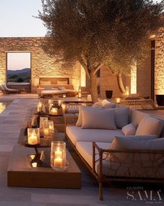 an outdoor living area with candles lit up in front of the couches and tables