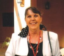 a woman standing in front of a building with a smile on her face and wearing a polka dot scarf around her neck