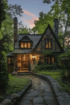 a stone path leading to a house in the woods at night with light shining on it's windows